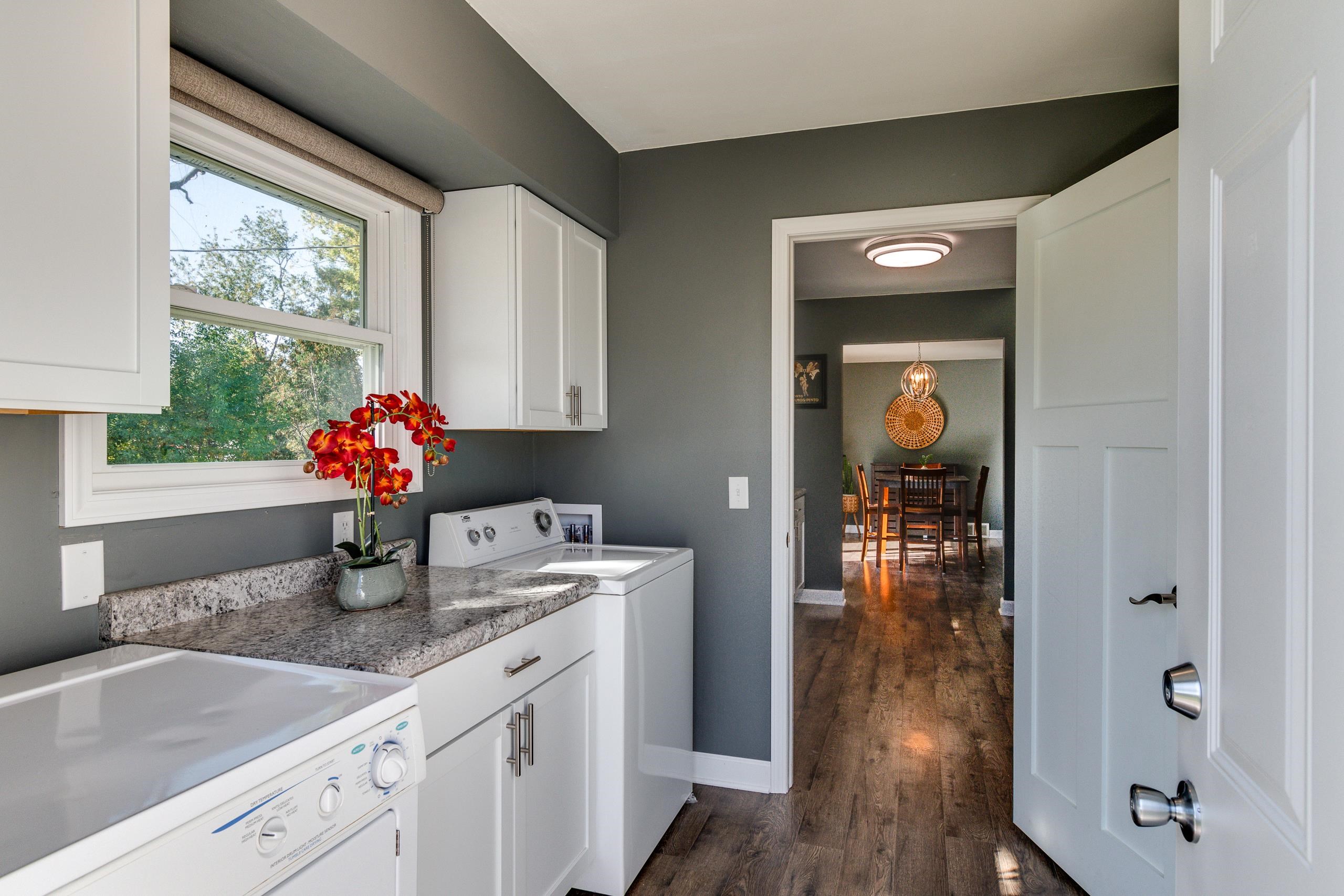 Laundry room with white appliances, granite counter, and a doorway to the dining room.