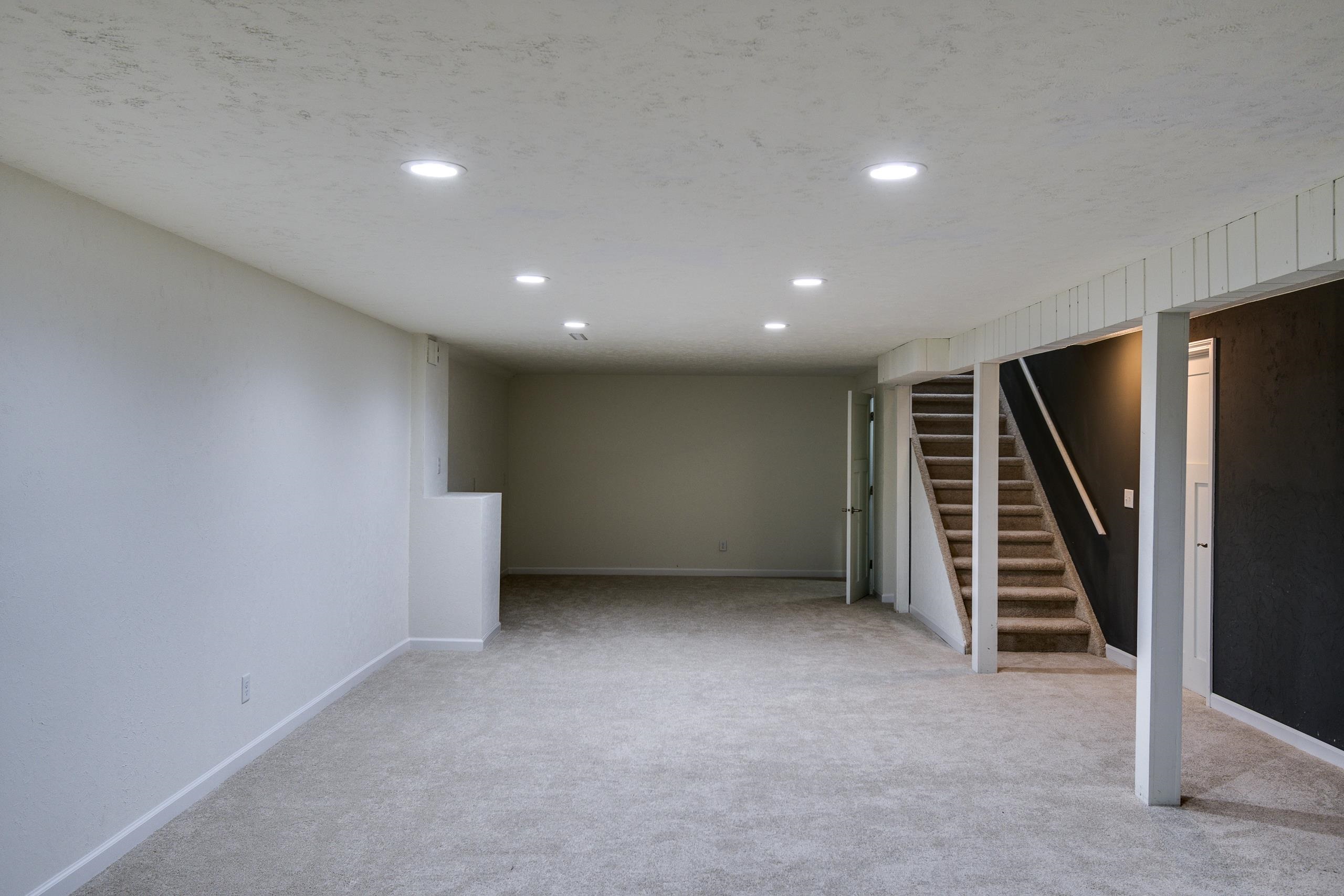 Unfurnished carpeted basement with recessed lights and a staircase along the right wall.
