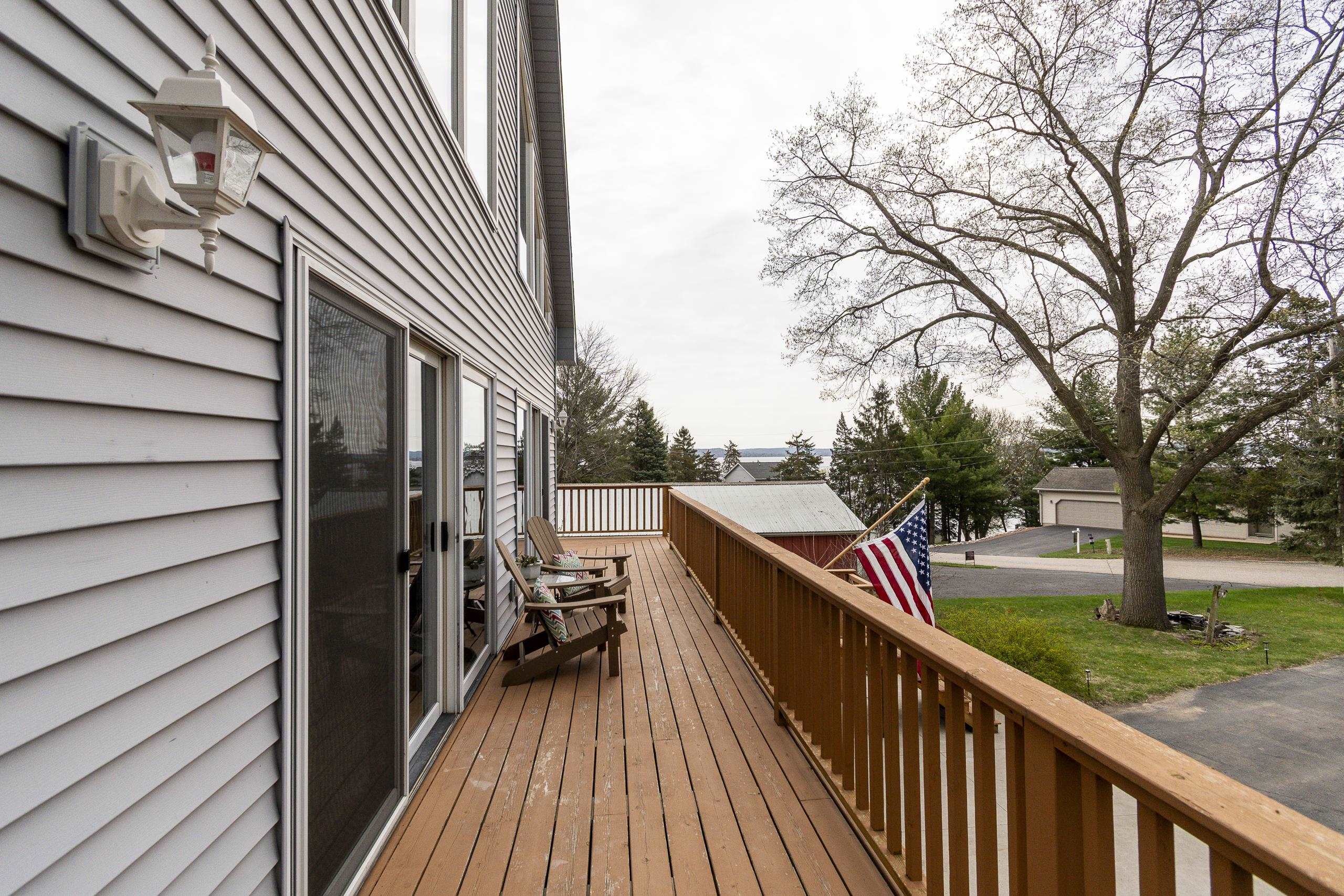 Wooden deck with Adirondack chairs and a view of the lake.