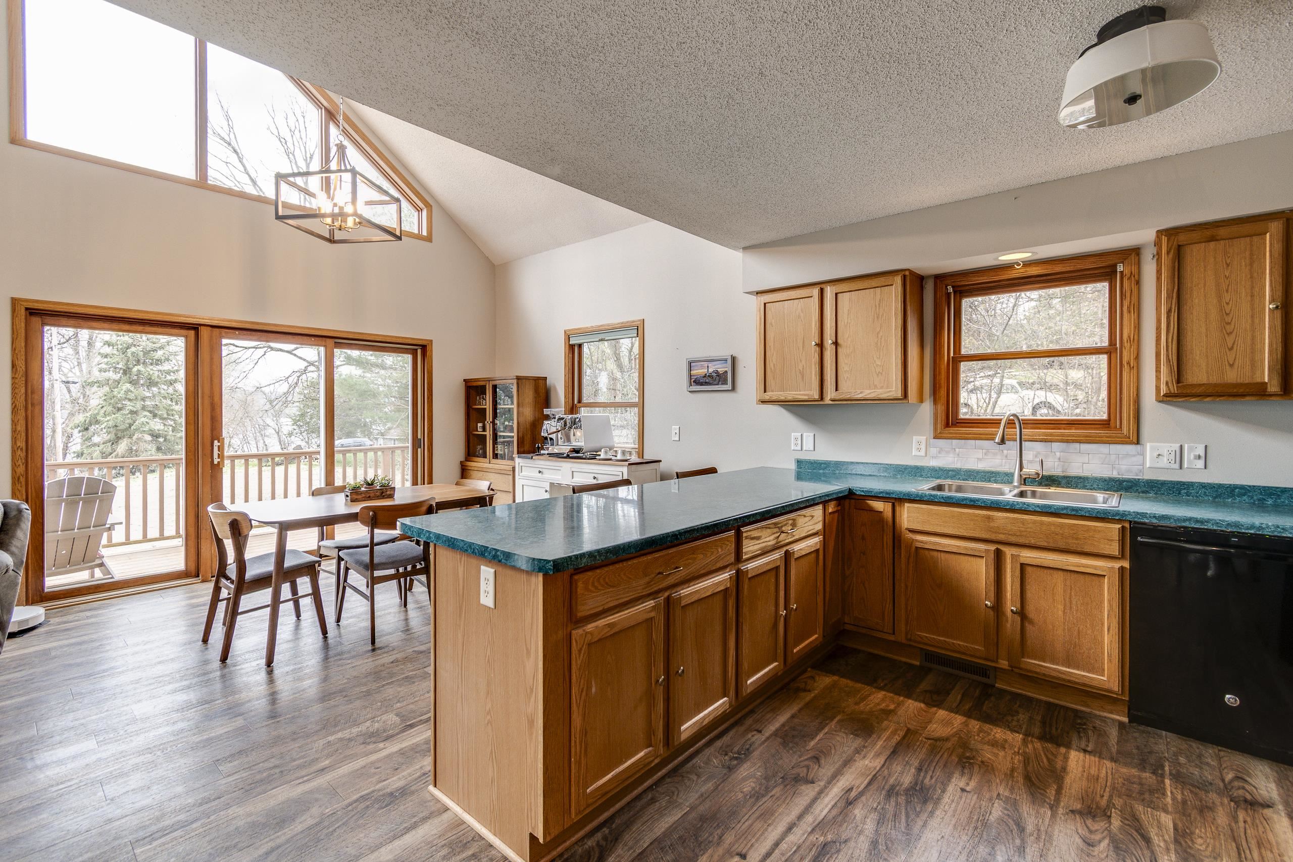 Kitchen with a large teal island, wood cabinetry, and sliding doors opening to a deck.