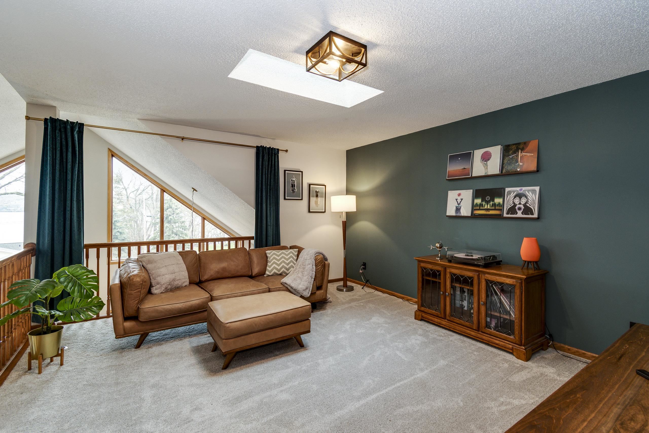 Living room with a leather sofa, teal accent wall, and large sloped window.