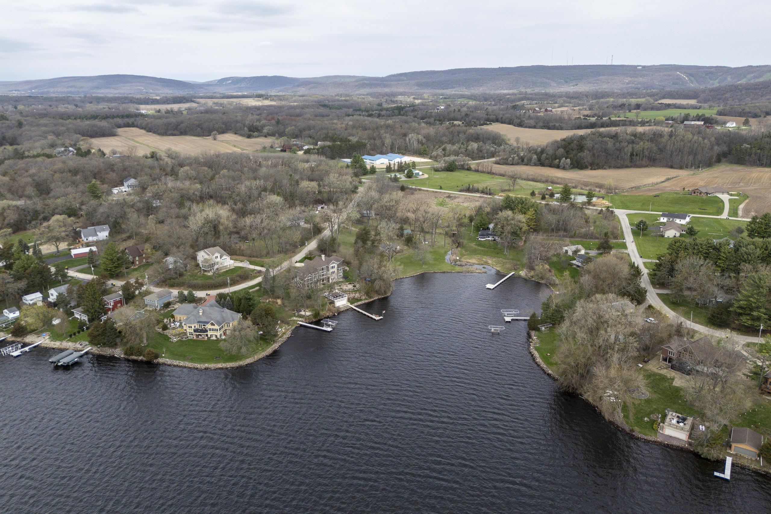 Aerial view of lakefront homes and docks along a wooded shoreline.