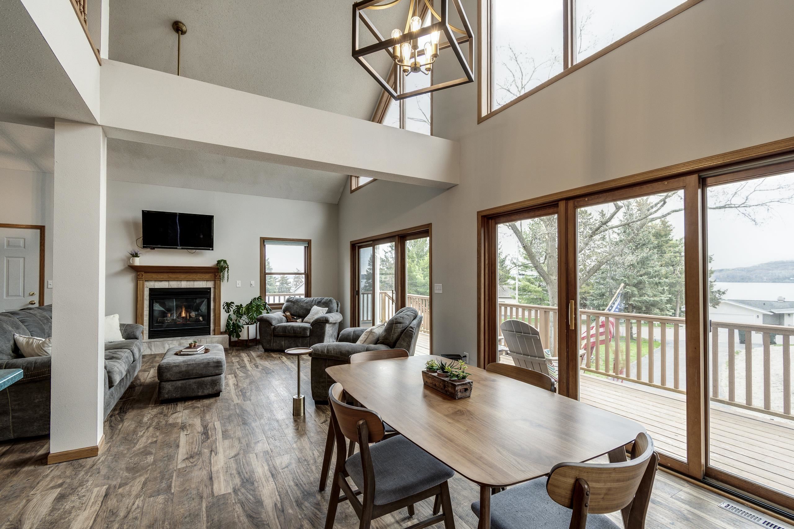 Living and dining room with vaulted ceilings, fireplace, and sliding doors overlooking the lake.