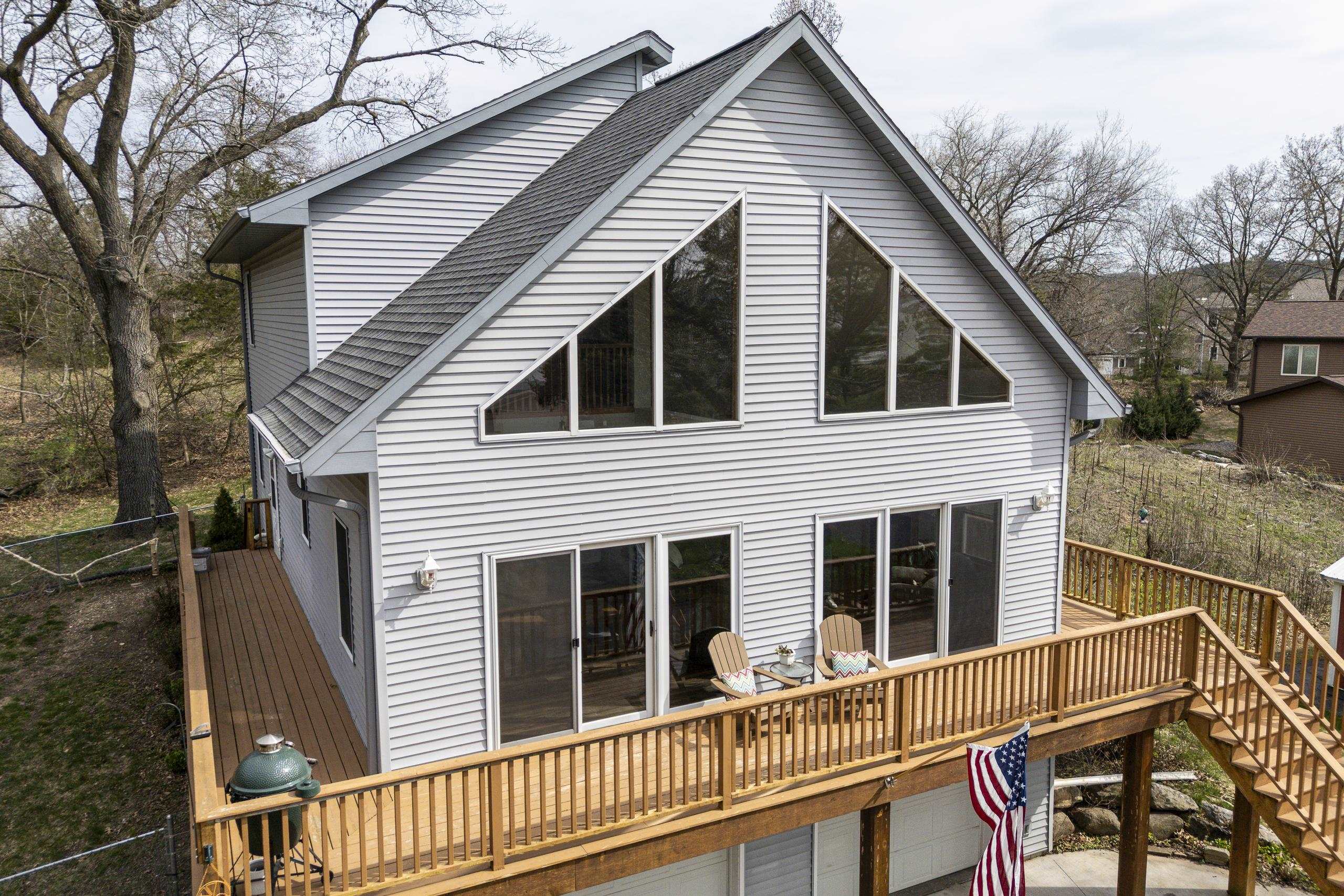 Gray gabled house with triangular windows and a spacious raised wooden deck.