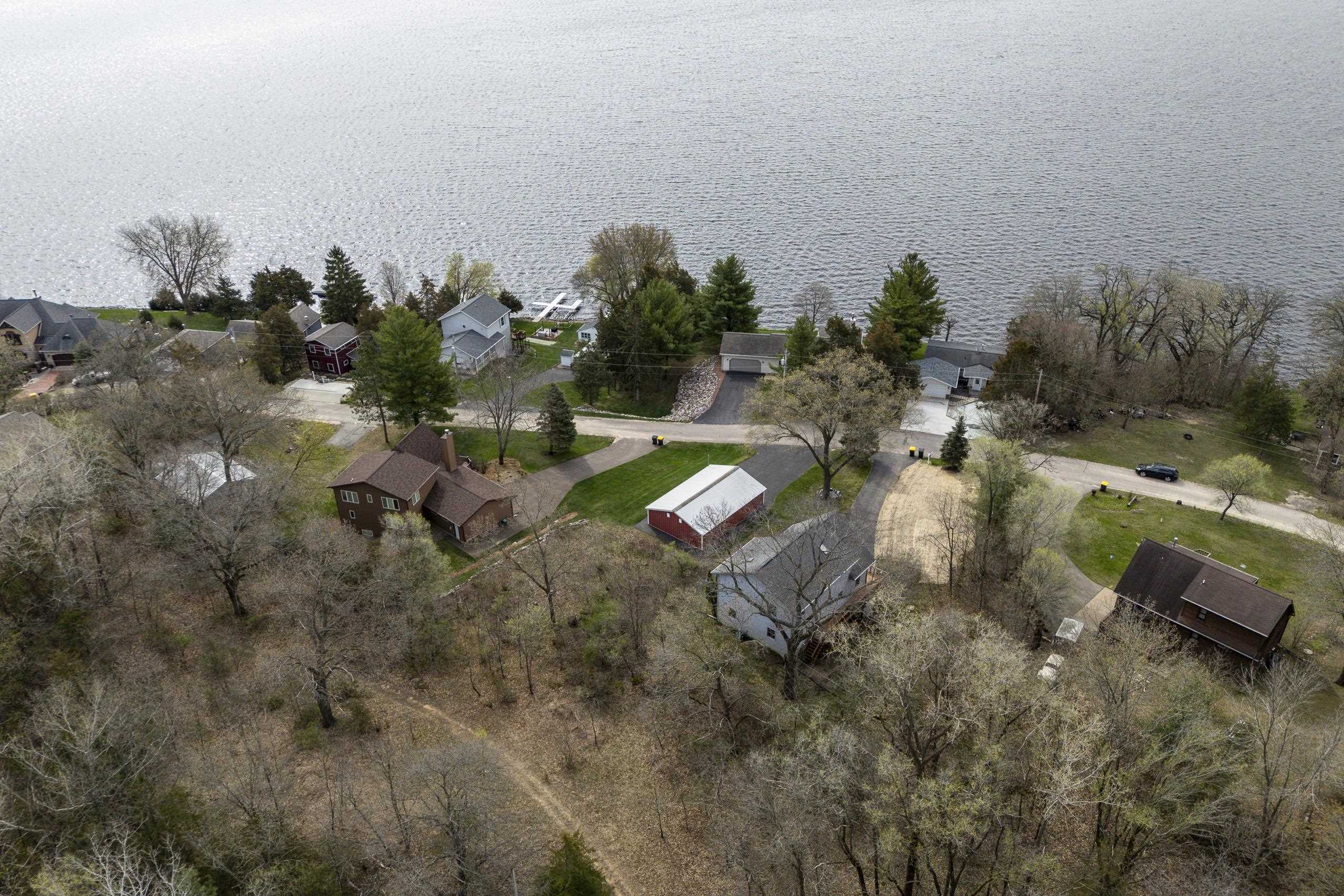 Aerial view of lakeside homes, a shoreline road, and docks extending into the water.