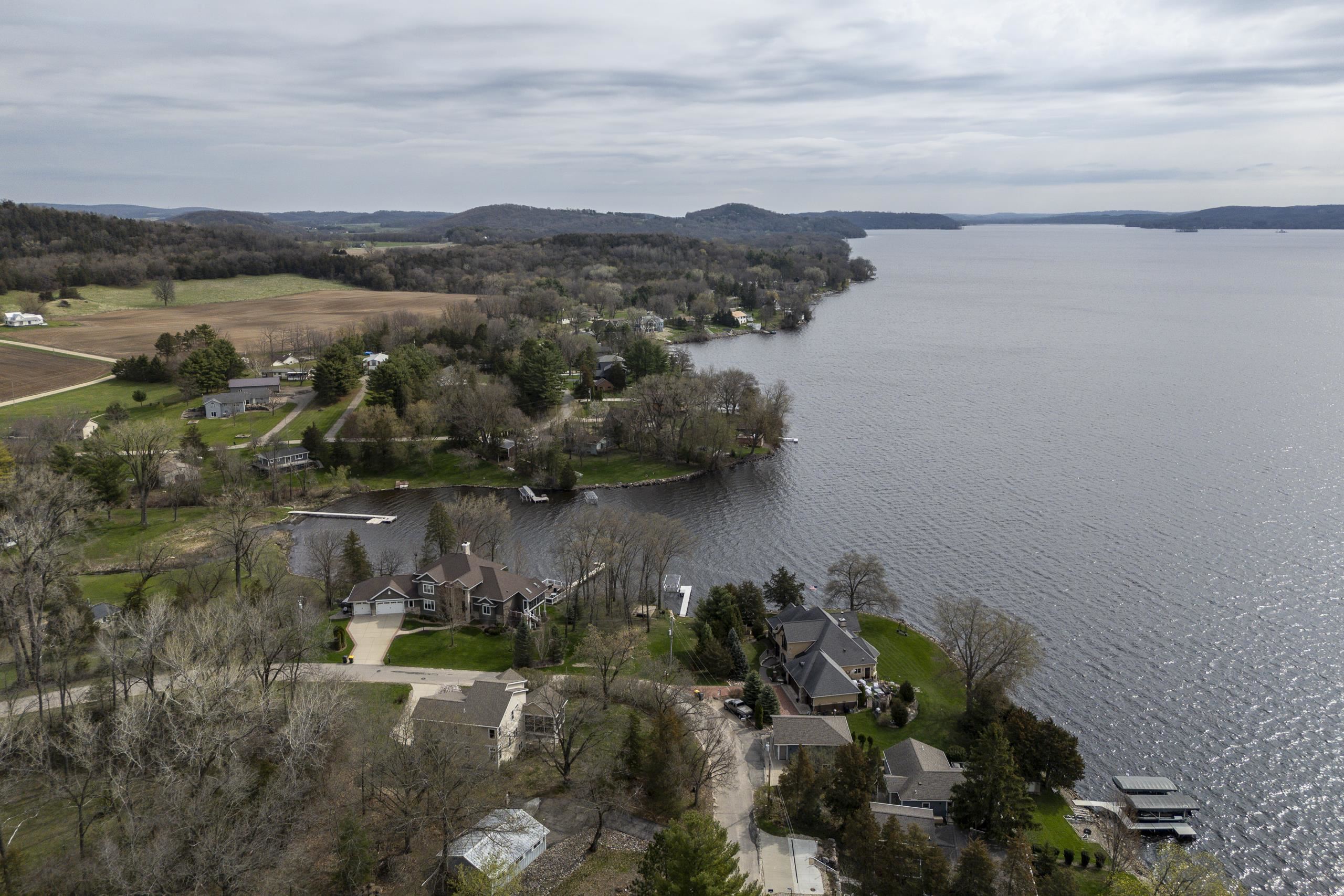 Aerial view of lakeside homes along a wooded shoreline, with docks extending into the lake.