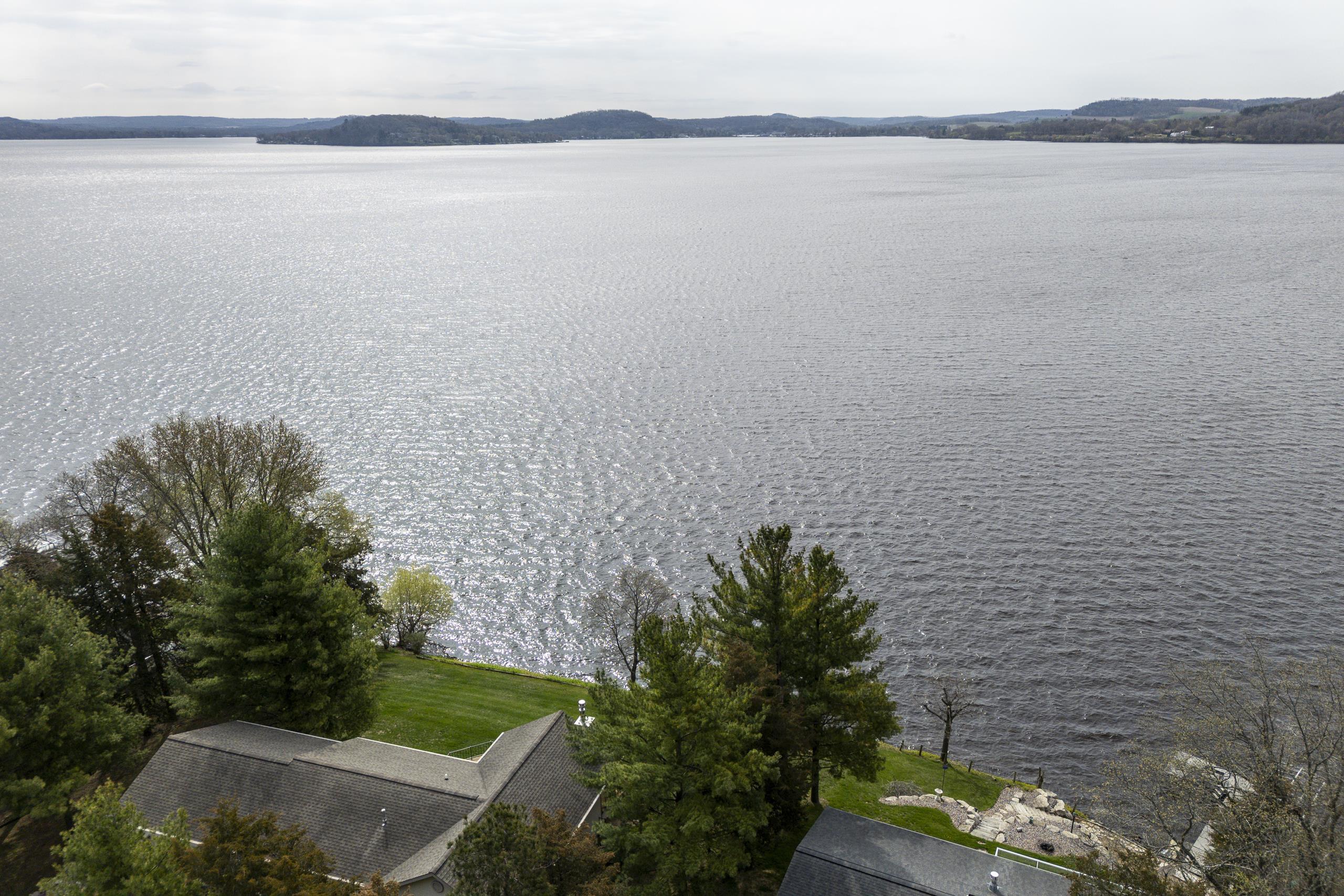 Lakefront property with a broad lake view, wooded lawn, and rocky shoreline.