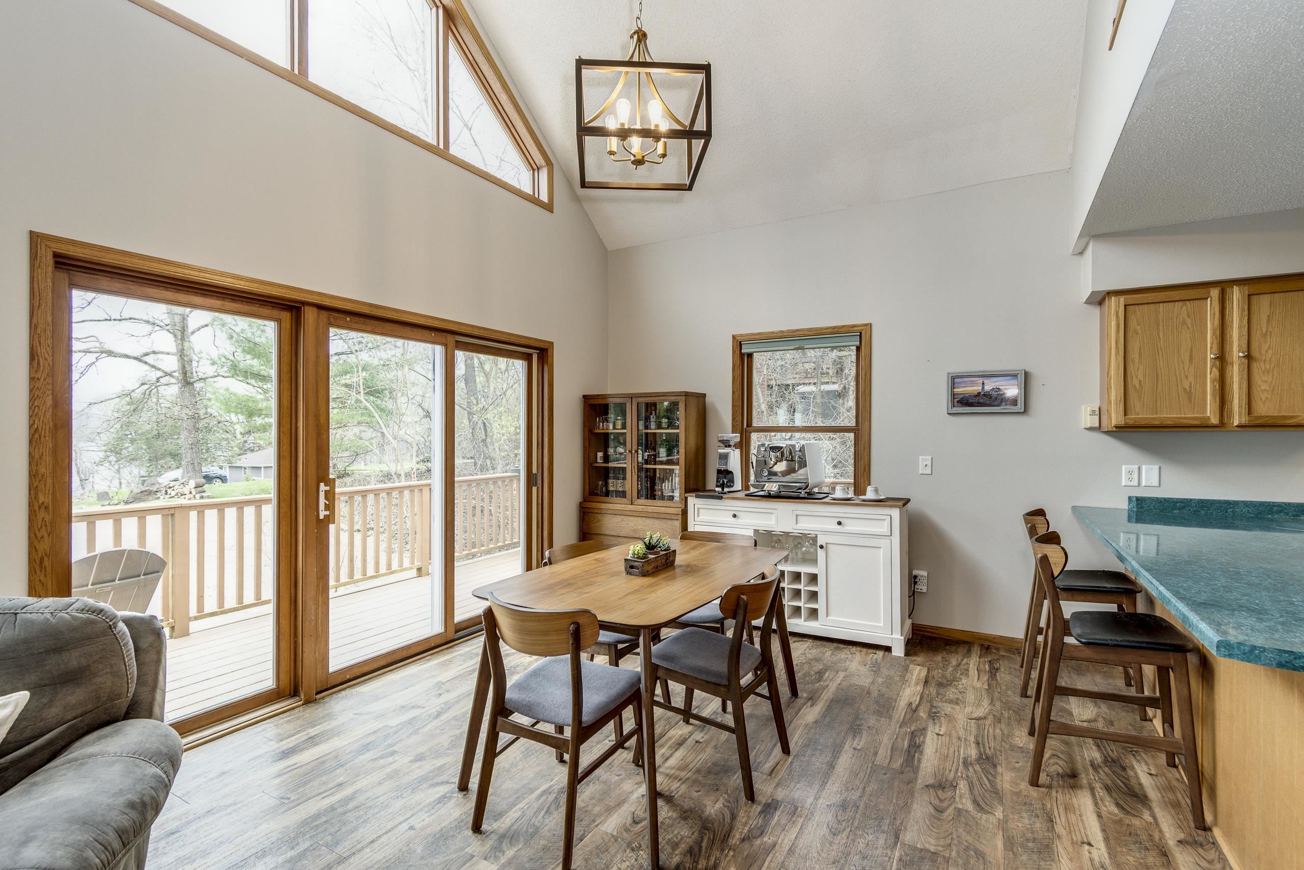 Dining area with wood table beside sliding glass doors opening onto a deck.