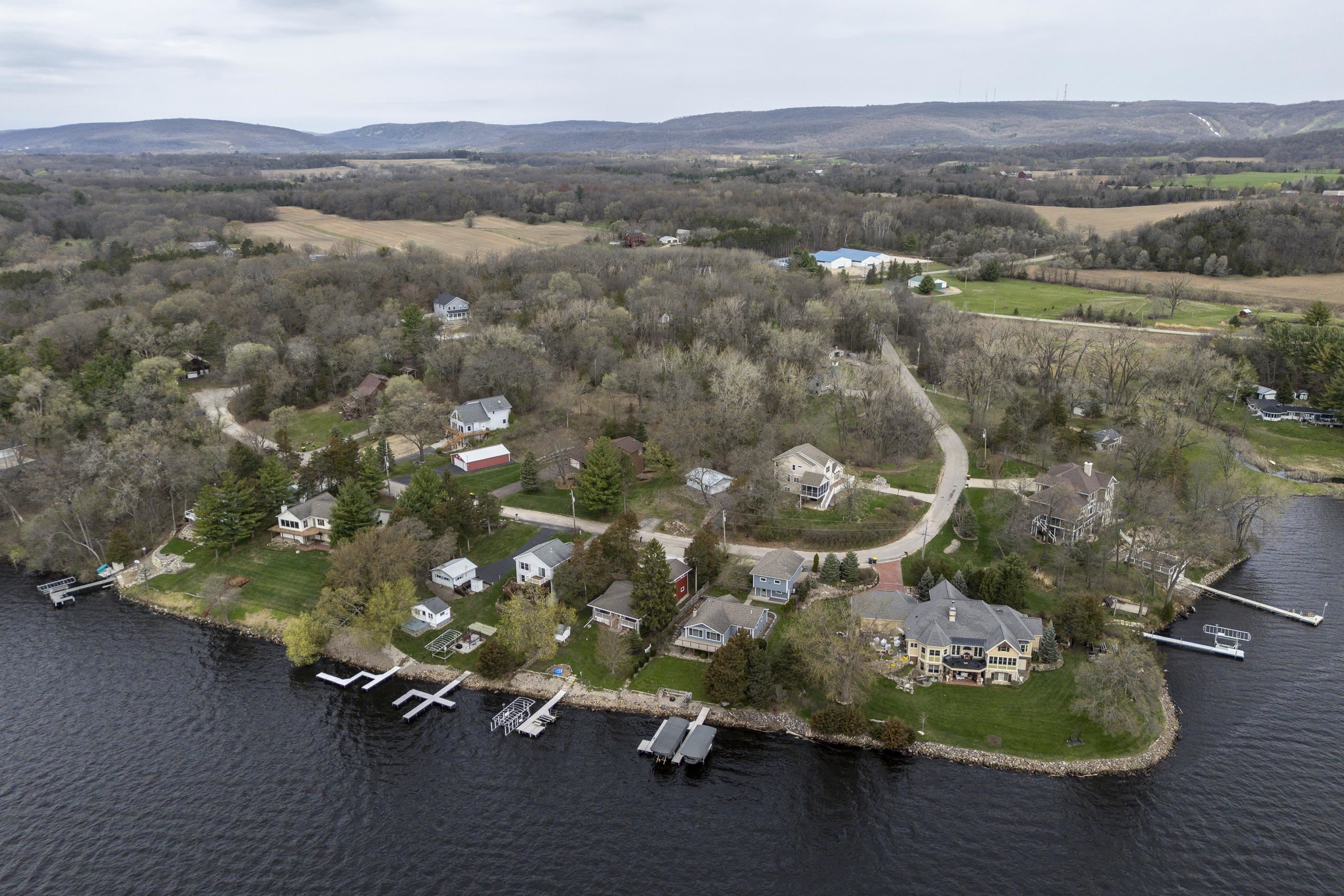Aerial view of lakeside homes and docks along a wooded, curving shoreline.