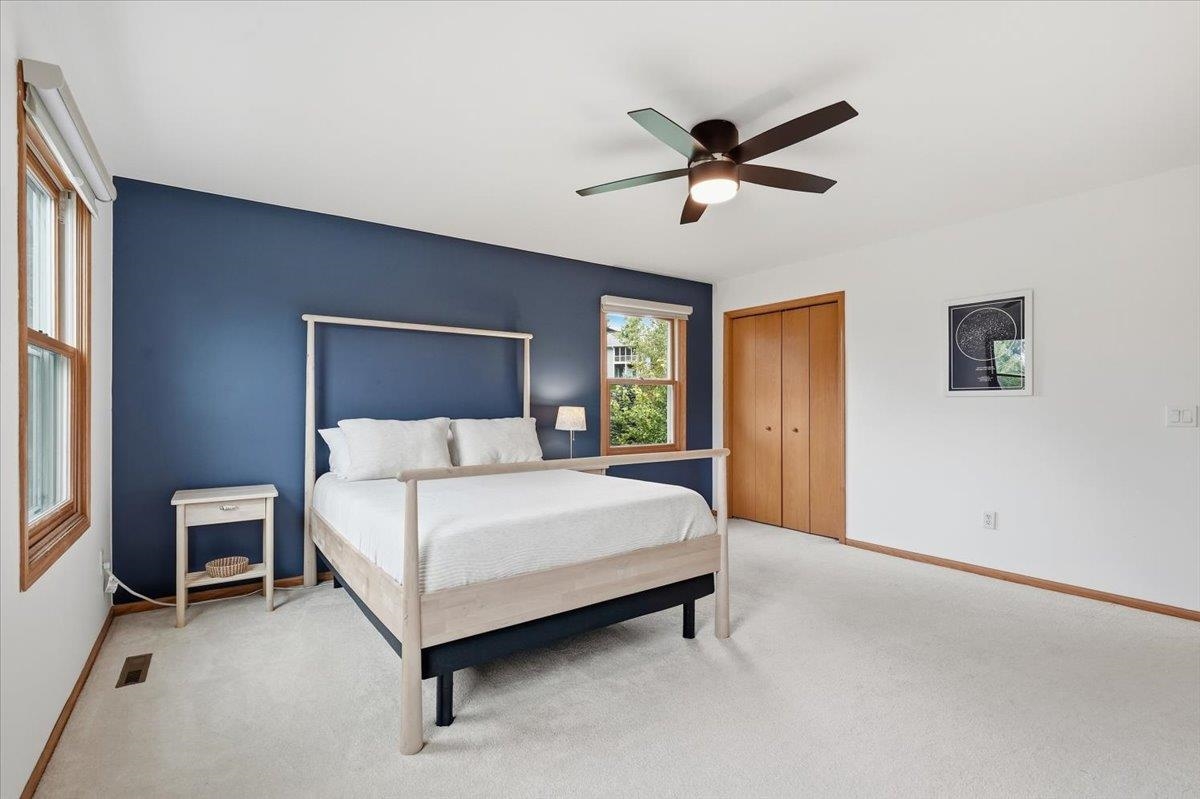 Bedroom with a light wood bed, navy accent wall, and two wood-trimmed windows.