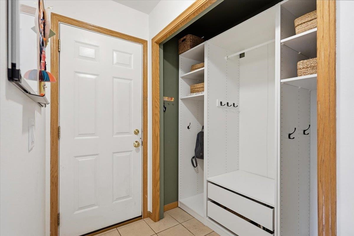 Entryway with a white paneled door and built-in cubbies, hooks, drawers, and woven baskets.