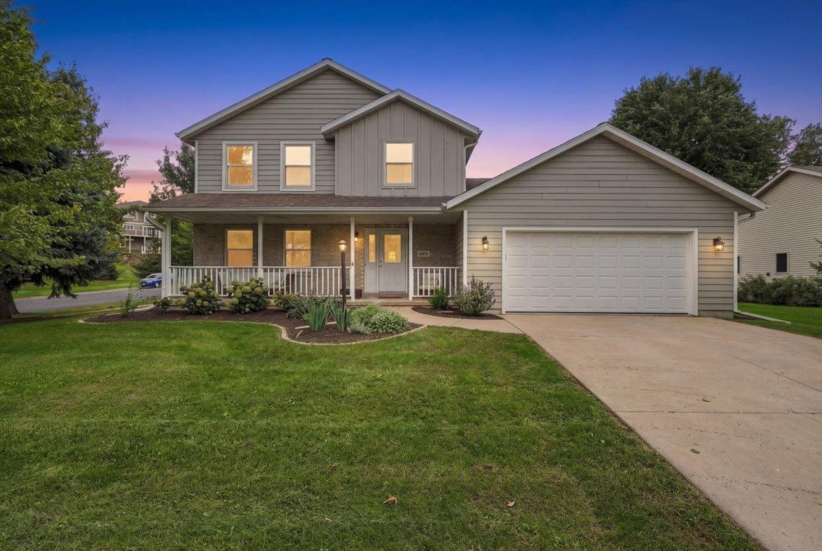 Two-story gray home with a covered porch and attached garage at dusk.