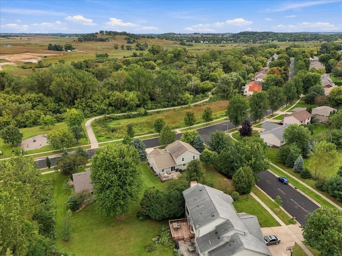 Aerial view of homes beside a tree-filled green space and winding walking path.