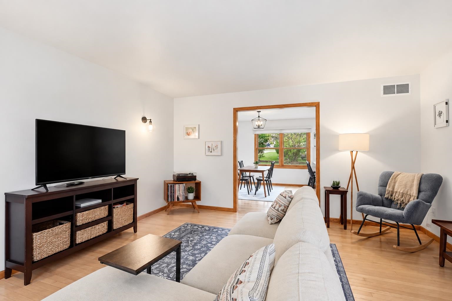 Furnished living room with a white sofa, large television, and wood-trimmed opening to the dining area.