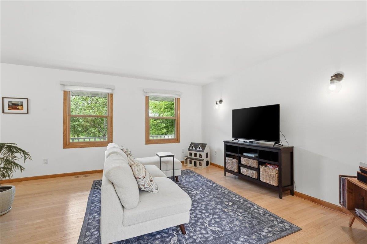 Living room with a white sofa, patterned rug, hardwood floors, and two wood-trimmed windows.