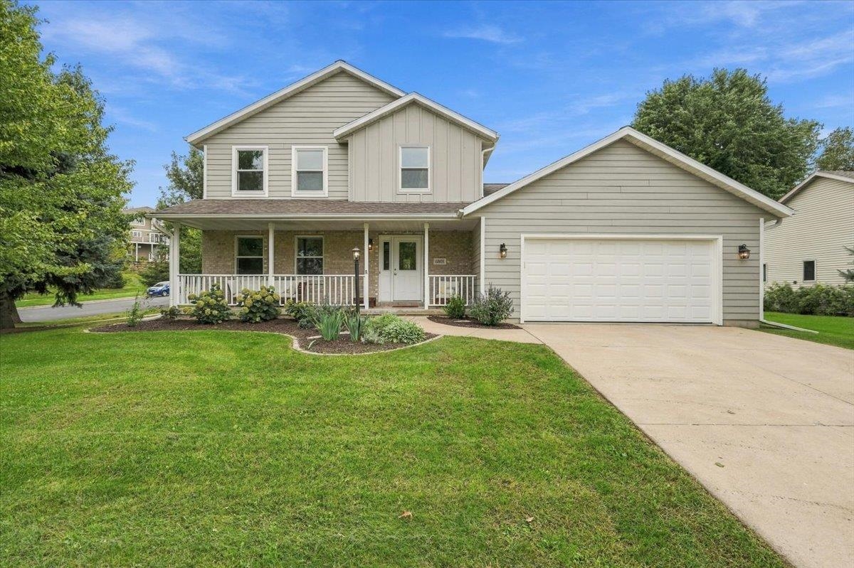 Two-story house with a covered porch, attached garage, and landscaped front lawn.