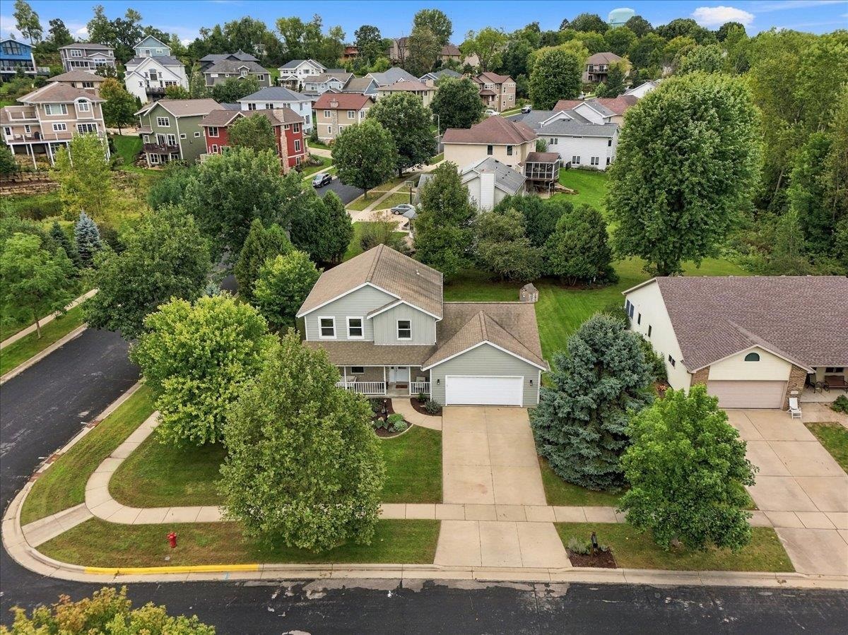 Aerial view of a gray two-story house with an attached garage and mature trees.