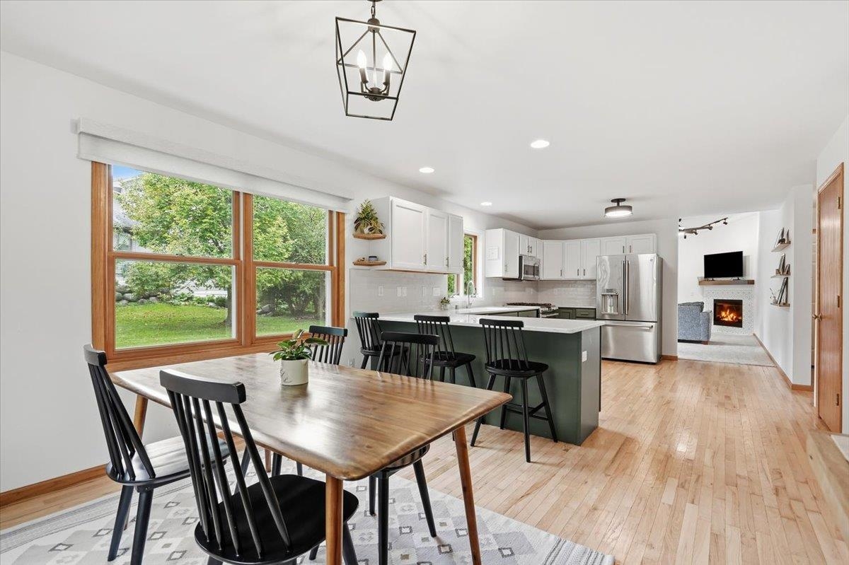 Open-plan kitchen and dining area with a dark green island and large windows overlooking the yard.