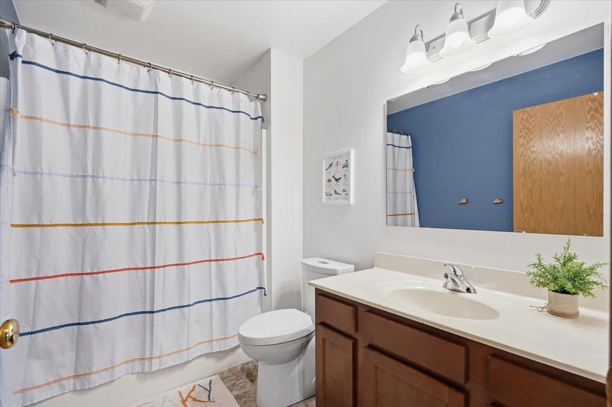 Bathroom with dark wood vanity, striped shower curtain, and blue accent wall reflected in the mirror.