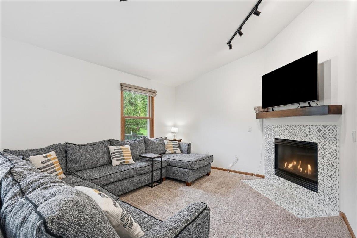 Living room with a gray sectional and a patterned-tile fireplace beneath a wall-mounted television.