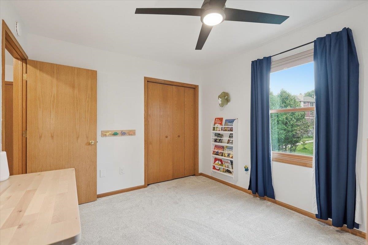 Bedroom with a wood closet, ceiling fan, navy curtains, and a window overlooking trees.