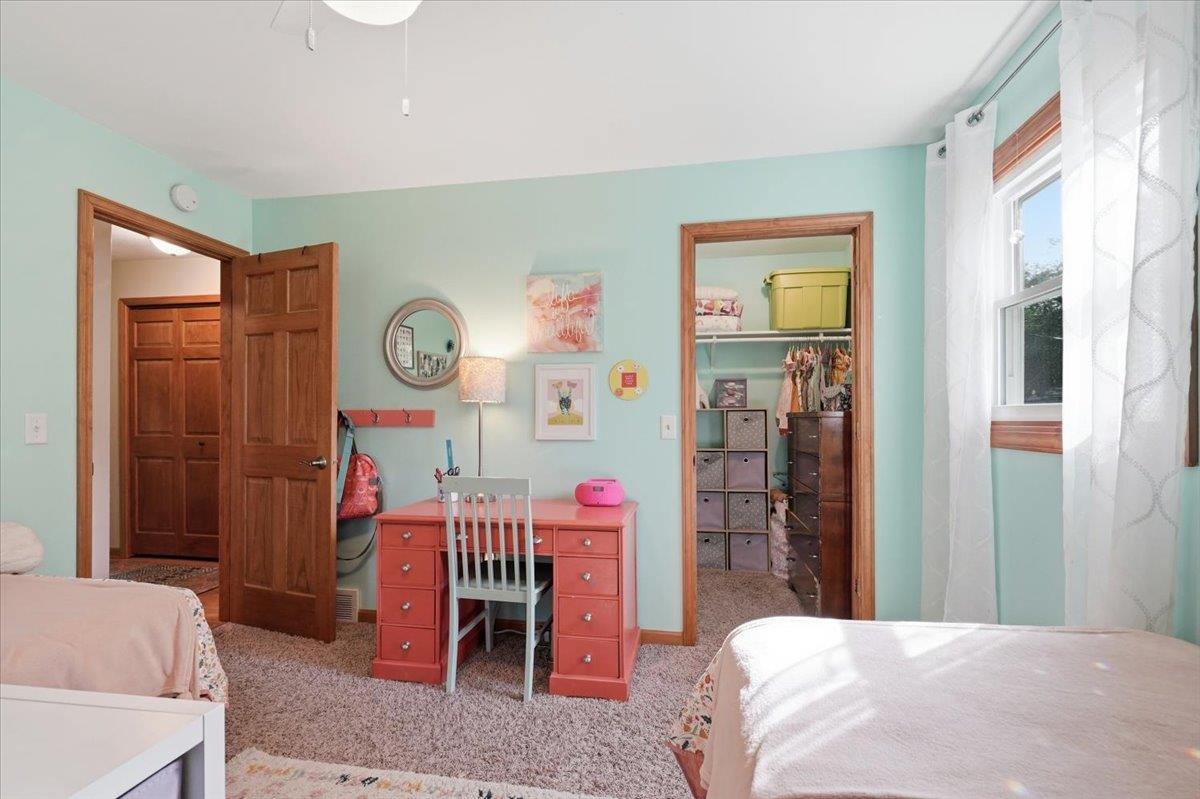 Bedroom with mint walls, twin beds, a coral desk, and an open clothes closet.
