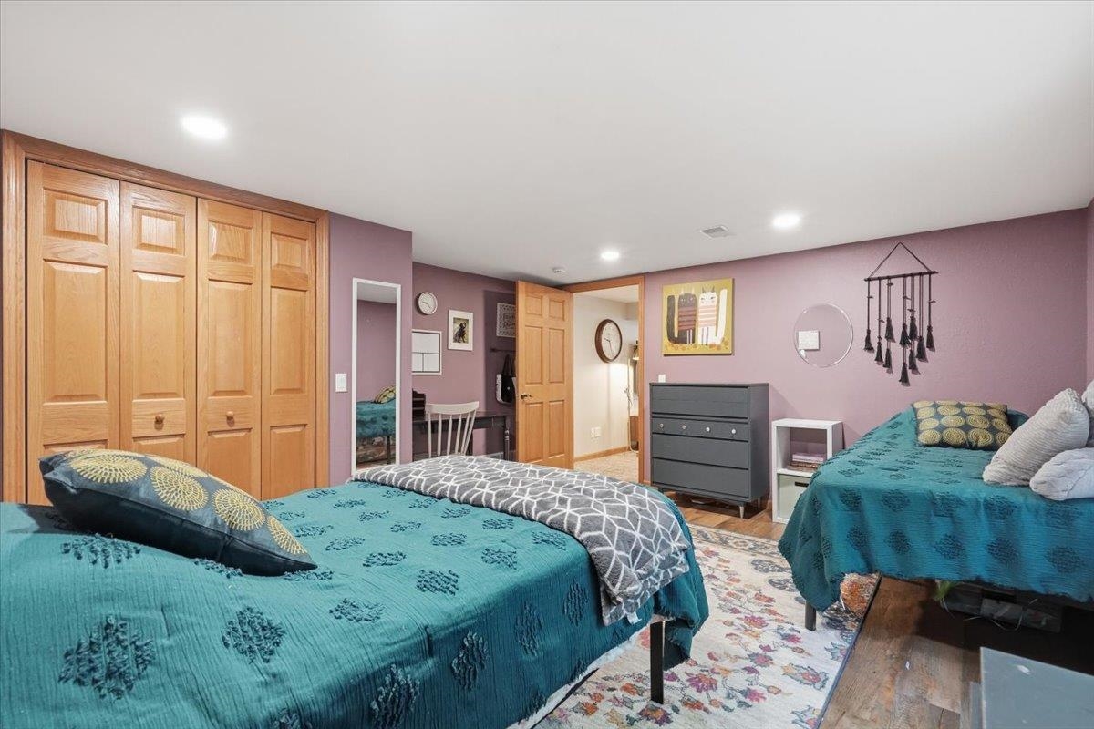 Bedroom with two teal-covered beds, wooden closets, mauve walls, and a floral rug.