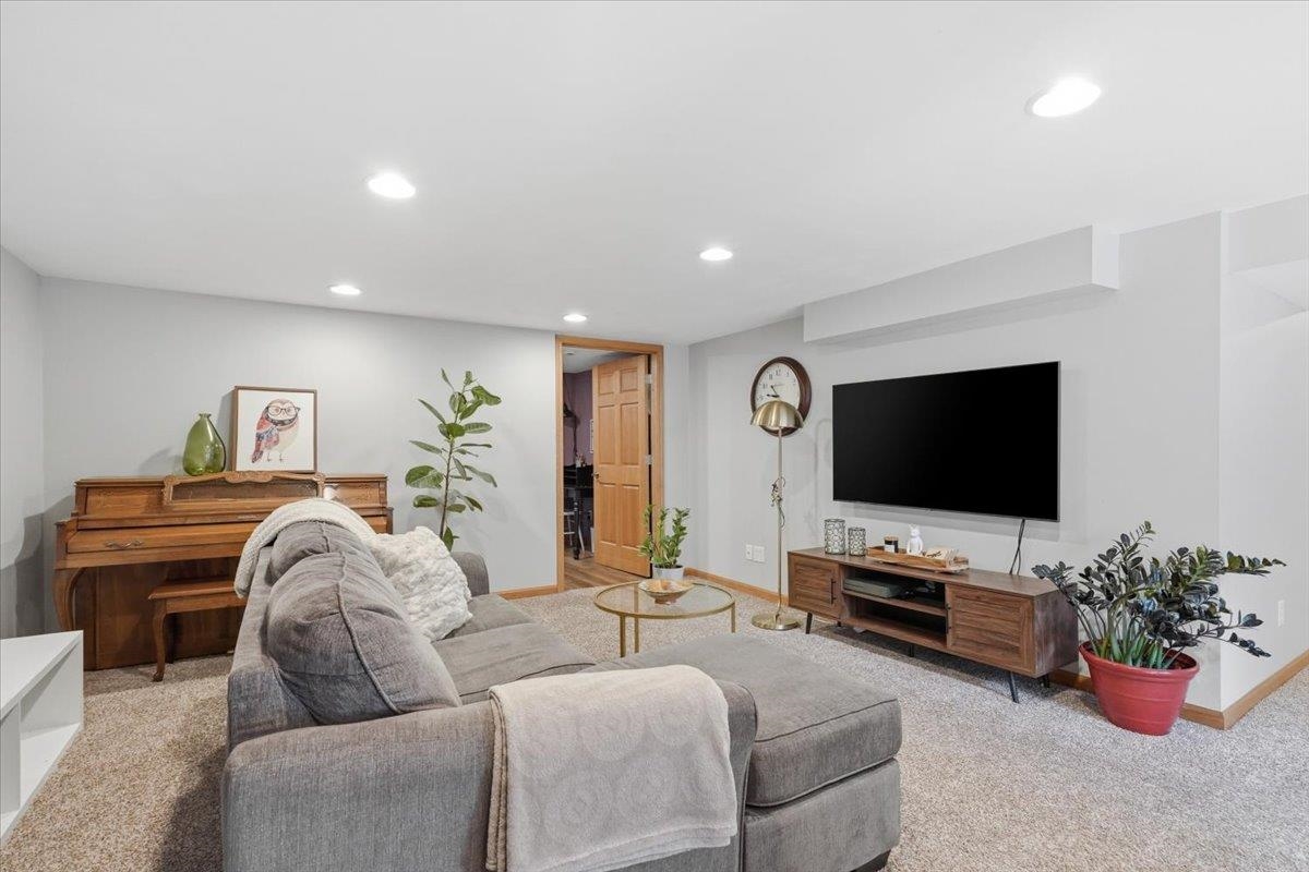 Living room with a gray sectional, wooden piano, and wall-mounted television.
