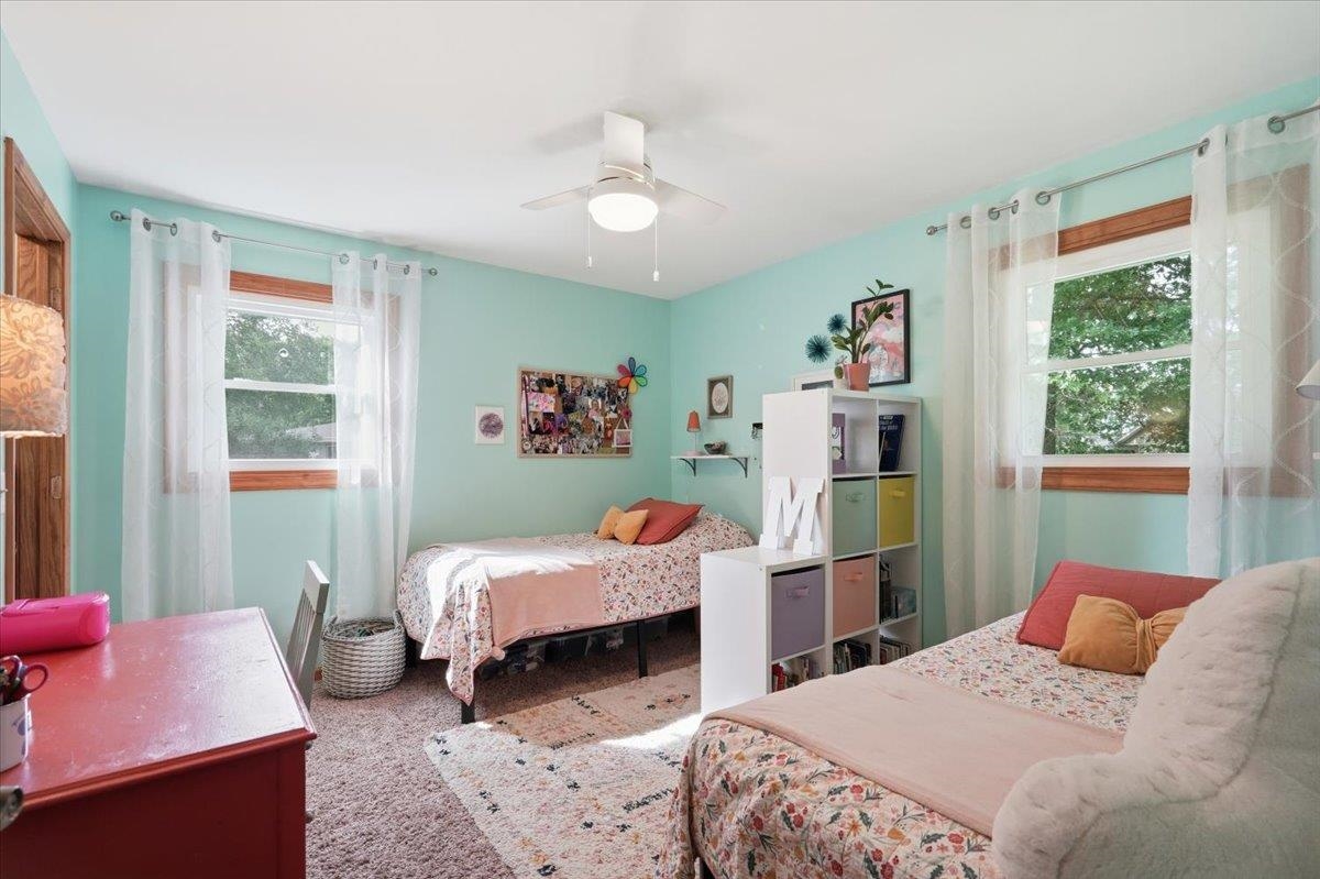 Bedroom with two floral-covered beds, aqua walls, and a white cube shelf.