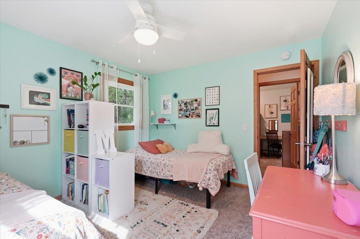 Bedroom with mint-green walls, two beds, a white cubby bookshelf, and a pink desk.