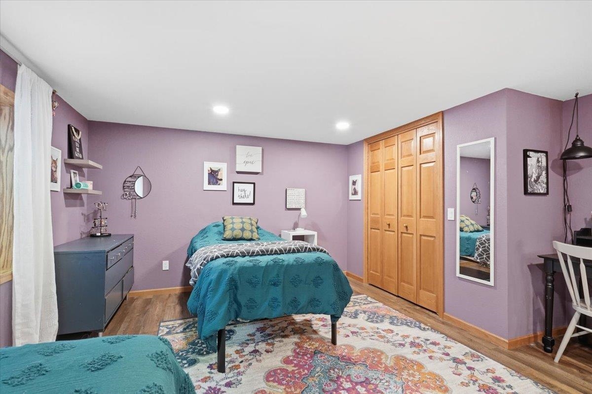 Bedroom with lavender walls, a teal-covered bed, wooden closet doors, and a colorful patterned rug.