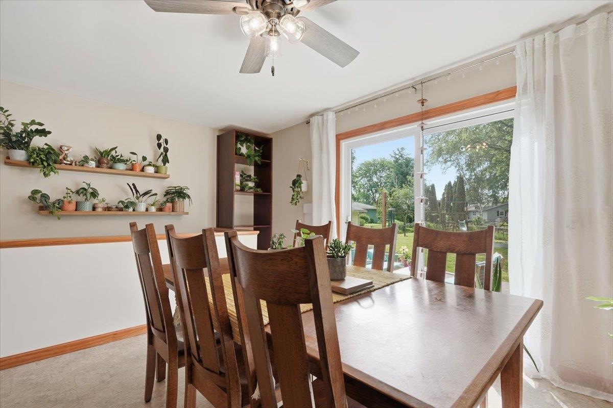 Dining room with a wooden table, plant-lined shelves, and a sliding glass door to the backyard.