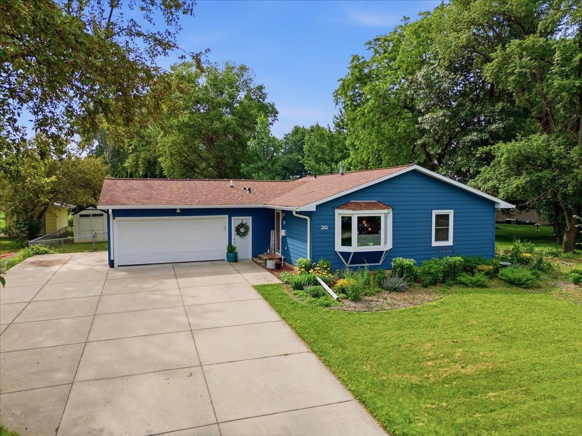 Blue single-story house with an attached two-car garage, wide driveway, and projecting bay window.
