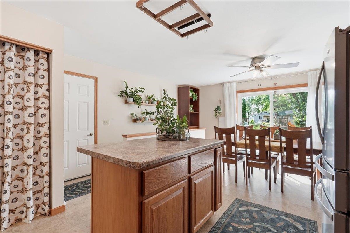 Kitchen island and dining area with wood cabinetry, plants, and sliding glass doors to a leafy backyard.