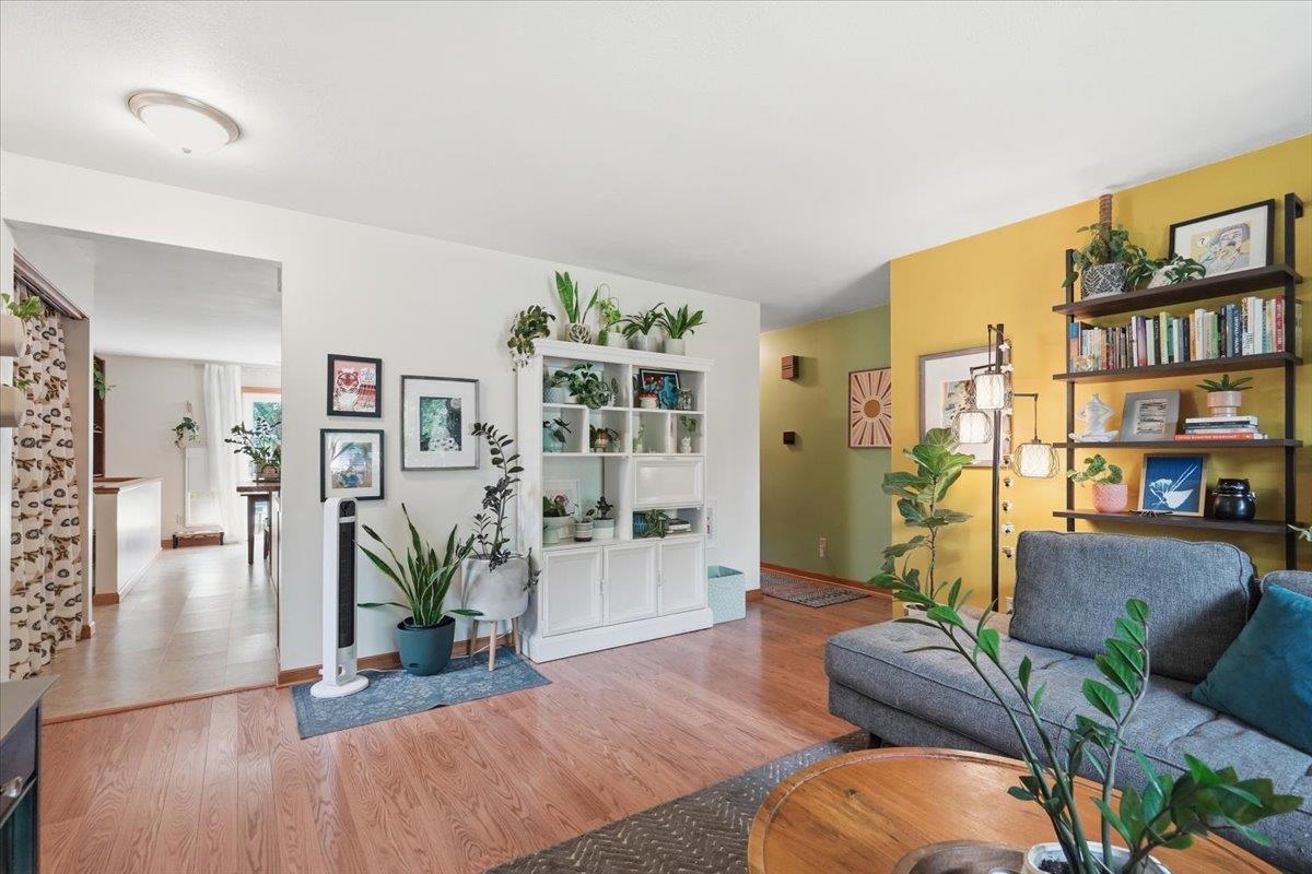Living room with a gray sectional, plant-filled white built-in cabinet, and mustard-yellow bookshelf wall.