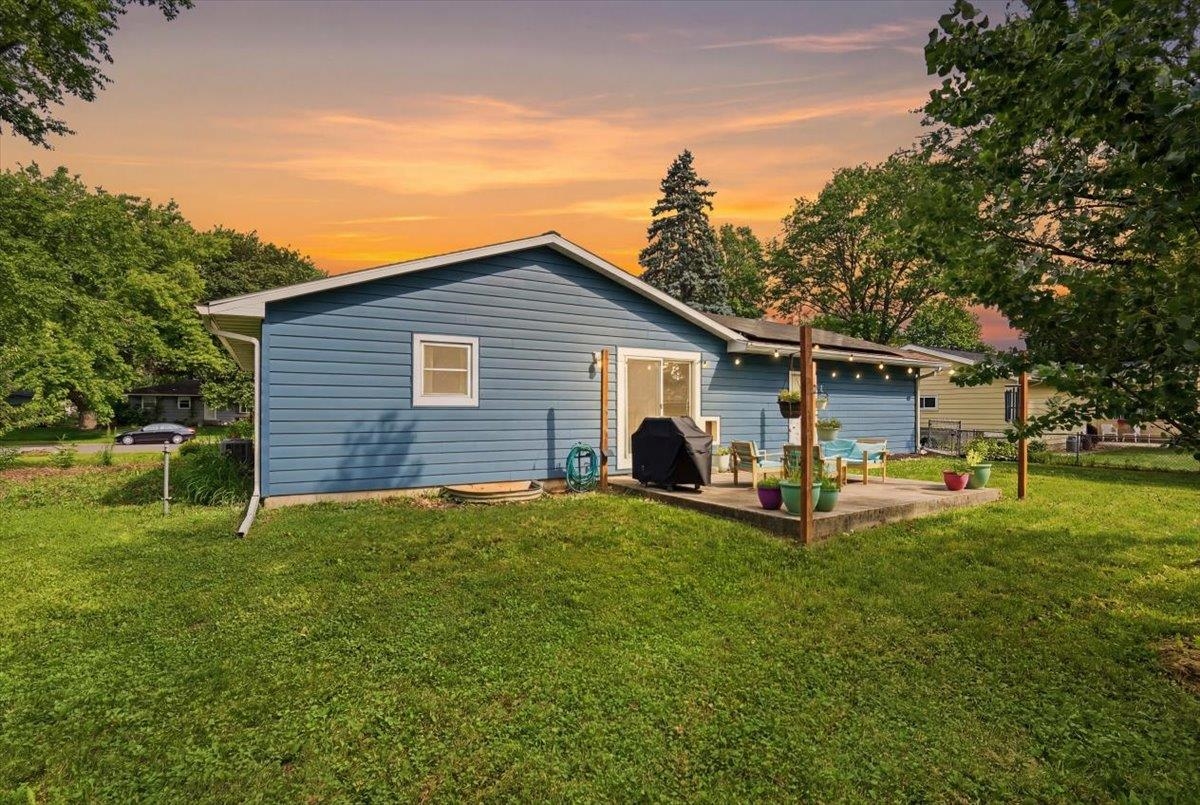 Blue single-story home with a covered patio and string lights at sunset.