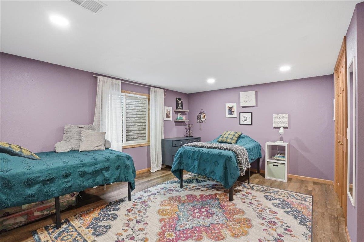 Bedroom with two teal-covered twin beds, lavender walls, and a colorful patterned rug.