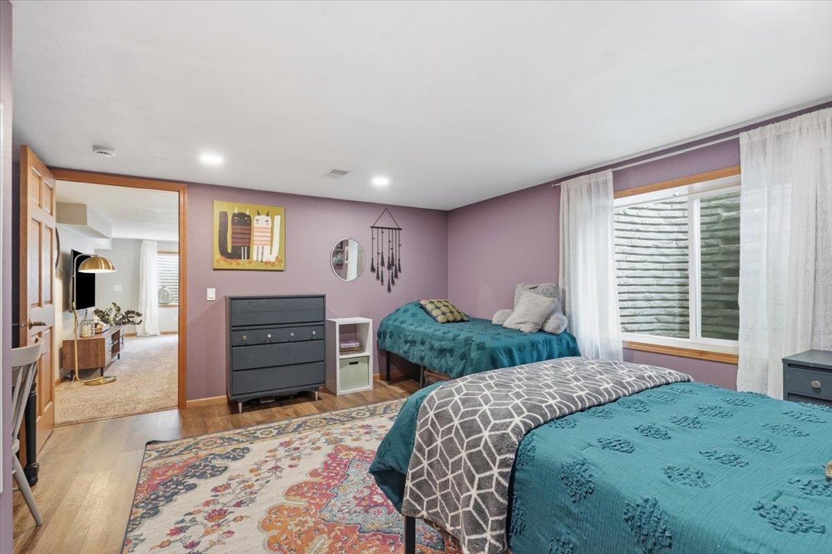 Bedroom with two teal-covered beds, mauve walls, and a large curtained window.