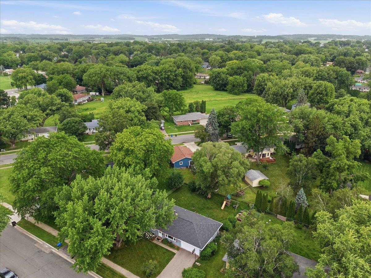 Aerial view of a leafy neighborhood, with a blue-gray house prominent among mature trees.