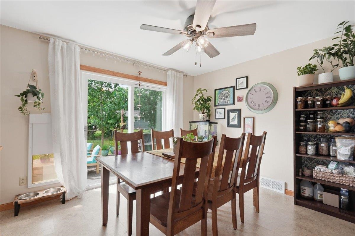 Dining room with a dark wood table, ceiling fan, and glass doors opening to the backyard.