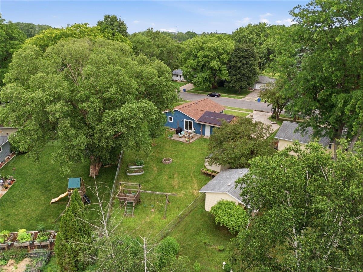 Backyard at 345 Kennedy Drive, with a blue solar-panelled home, mature trees, lawn, and playset.