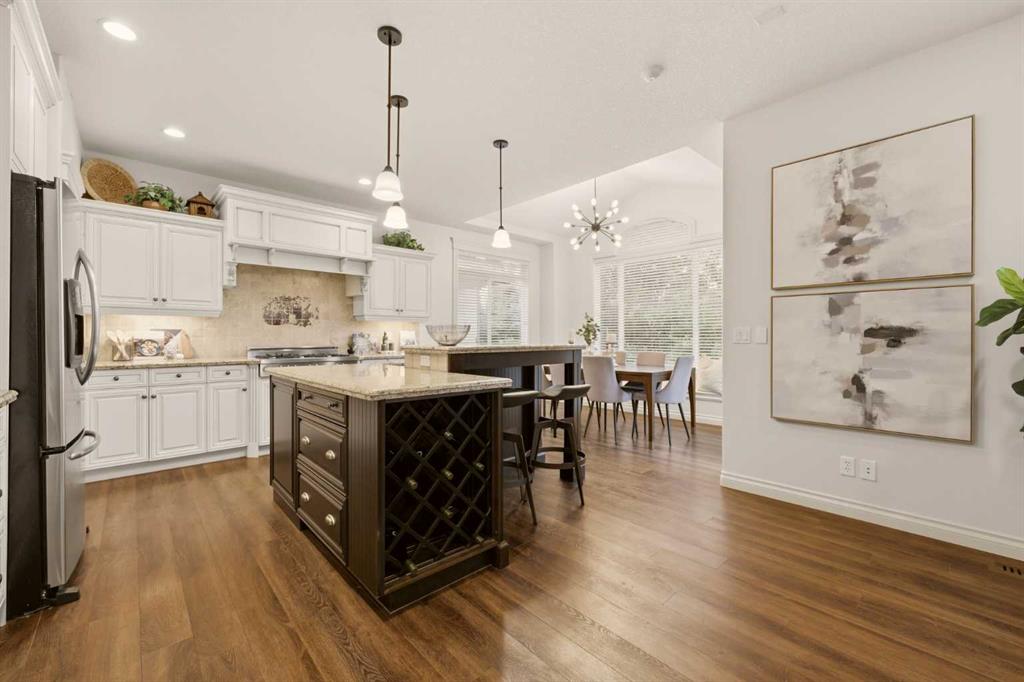 Kitchen with white cabinets, dark island and wine rack, opening to a bright dining area.