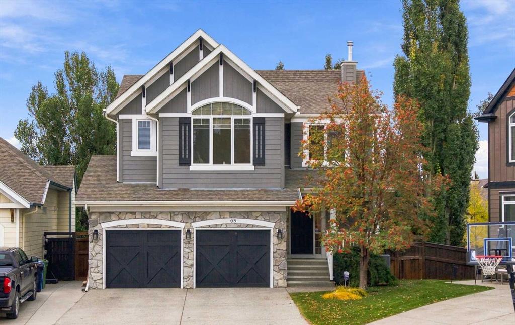 Gray two-story home with stone-faced double garage, peaked gables, and autumn trees.