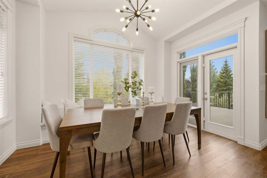 Dining room with a wood table, upholstered chairs, large windows, and glass doors to a balcony.