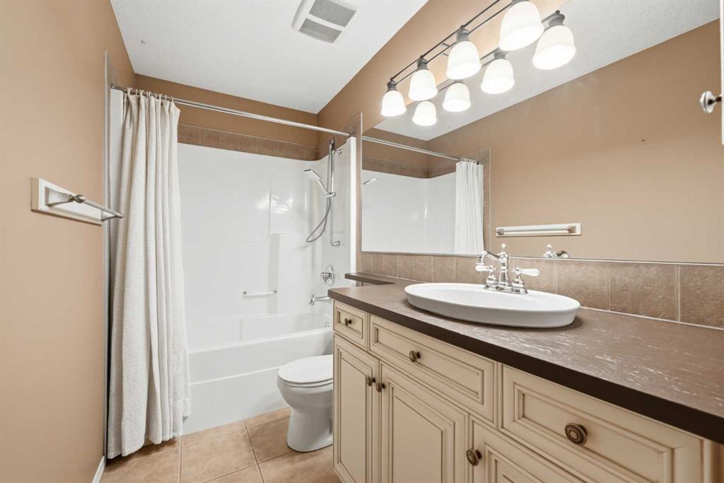 Bathroom with a curtained tub and shower beside a long cream vanity and oval sink.