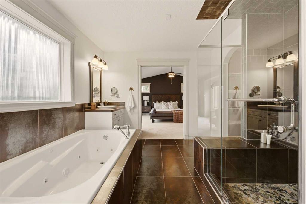 Ensuite bathroom with a jetted tub, glass shower, and bedroom visible through the doorway.