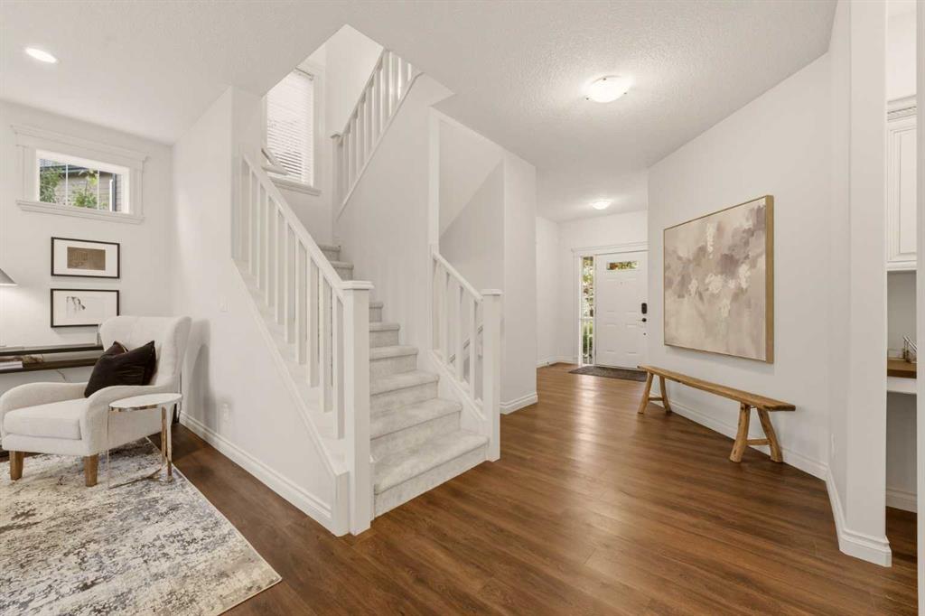 Entry hall with a carpeted staircase, hardwood floors, and a white front door.