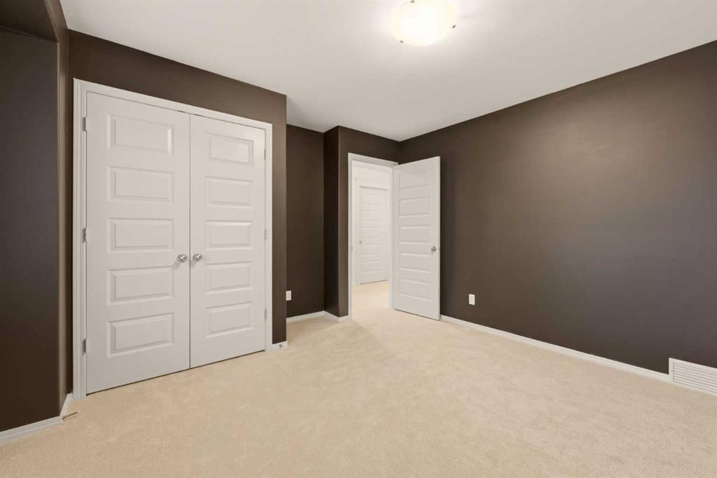 Empty carpeted bedroom with dark walls, white double closet doors, and an open doorway.