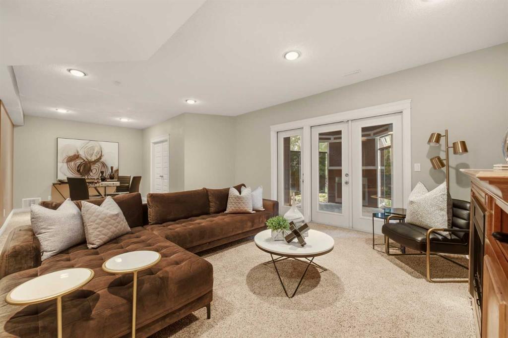 Staged living room with a brown sectional, round coffee table, and French doors.