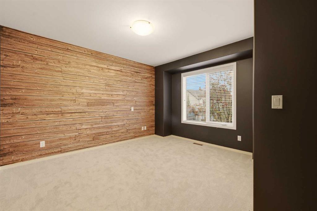 Empty room with a wood-plank accent wall and a window with white blinds.